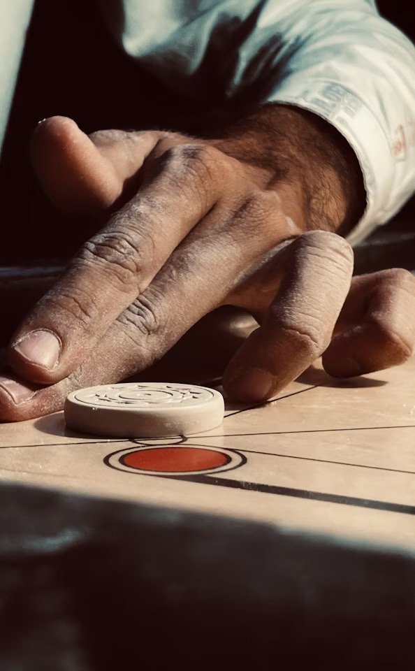 A hand about to flick a carrom coin
