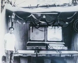 Black and white photo of a man standing at a carrom board workshop